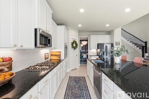 A kitchen with white cabinets and a black countertop.