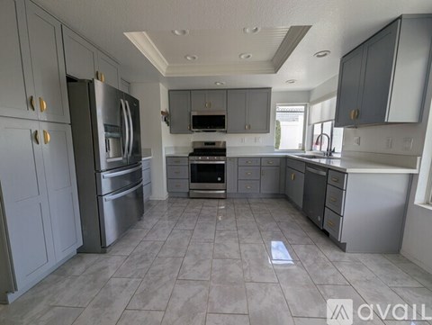 A kitchen with a tile floor and grey cabinets.