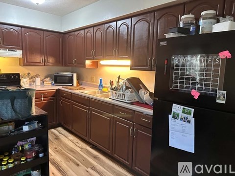 A kitchen with brown cabinets and a black fridge.