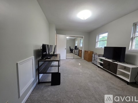 A living room with a television, a mirror, and a carpeted floor.
