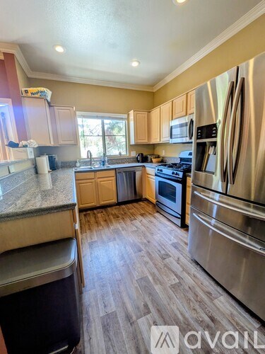 A kitchen with a stainless steel refrigerator and wooden flooring.