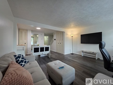 A living room with a grey couch and a white ottoman.