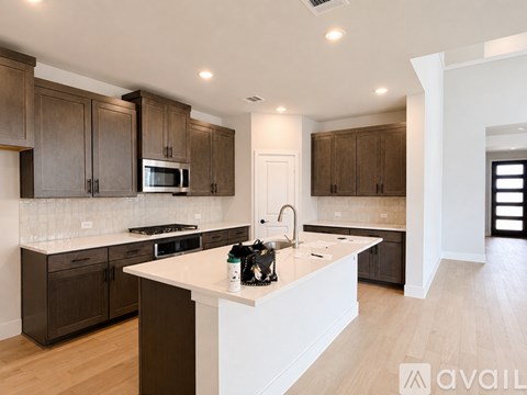 A modern kitchen with dark brown cabinets and white countertops.