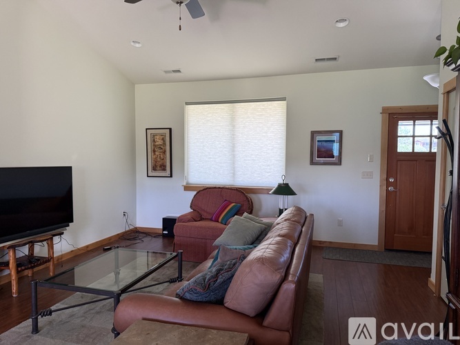 A living room with a brown leather couch and a glass coffee table.