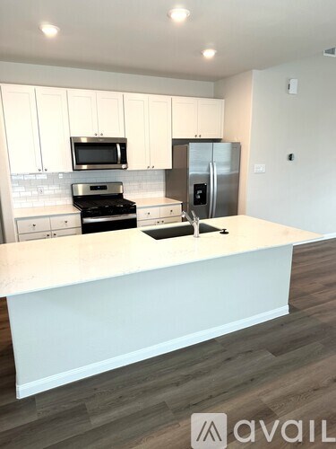 A kitchen with white cabinets and a white island.