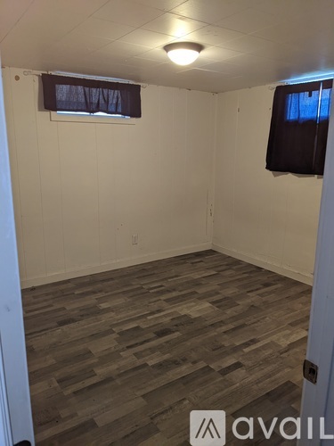 A room with a wooden floor and a window with a black curtain.