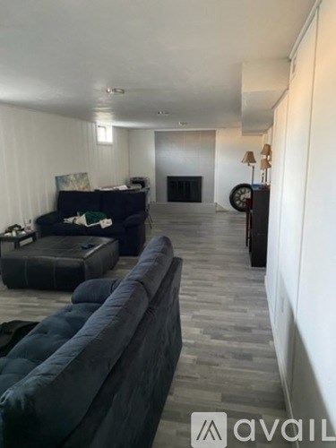 A living room with a grey couch and a black piano.