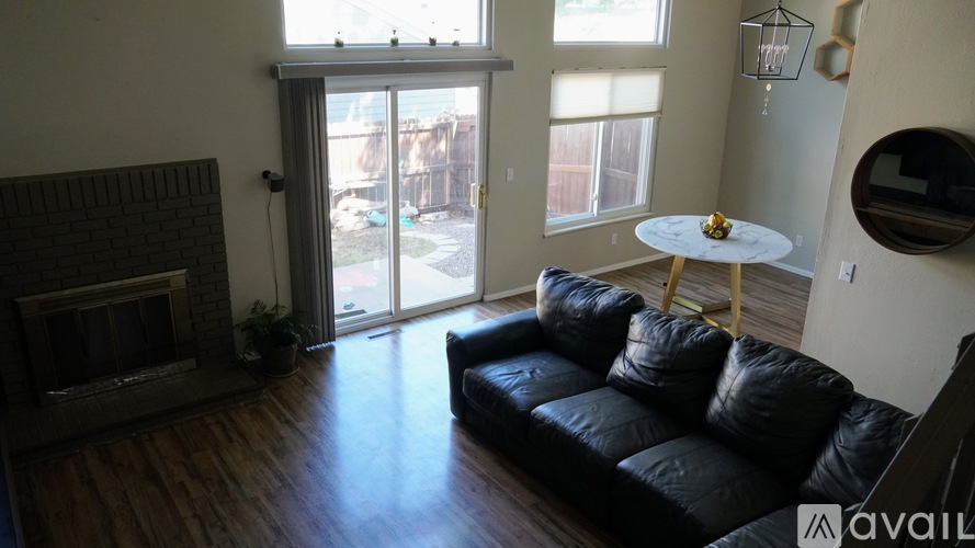 A living room with a black couch and a fireplace.