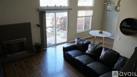 A living room with a black couch and a fireplace.