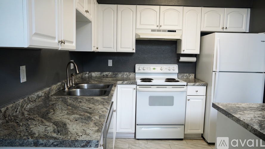 A kitchen with a granite countertop and white appliances.