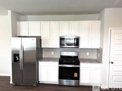 A kitchen with white cabinets and a stainless steel refrigerator.