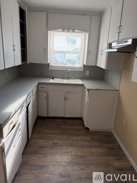 A kitchen with white cabinets and a window.