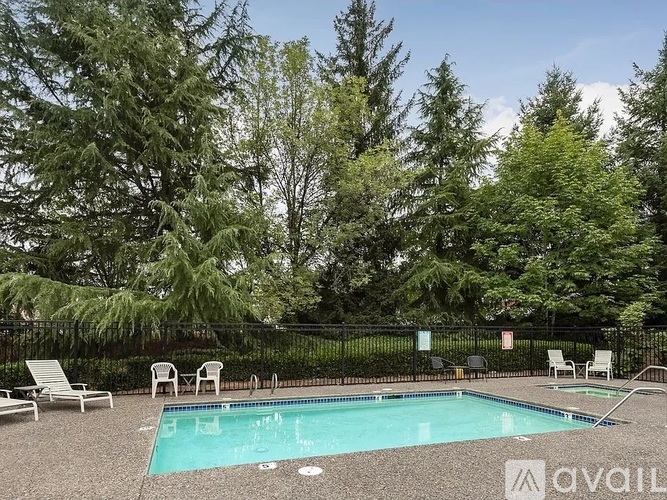 A pool surrounded by trees and chairs.