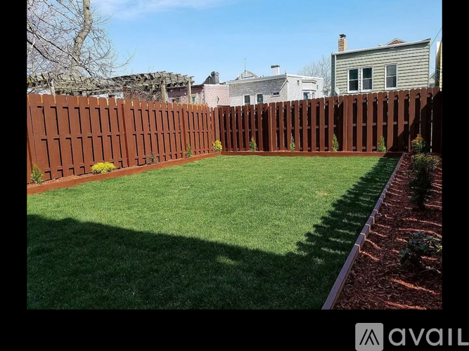 A backyard with a brown fence and green grass.