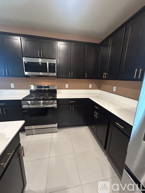 A kitchen with black cabinets and a stove top oven.