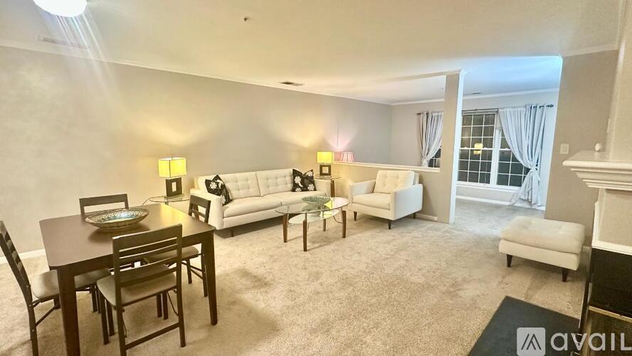 A living room with a dining table and chairs, a couch, a chair, and a lamp.