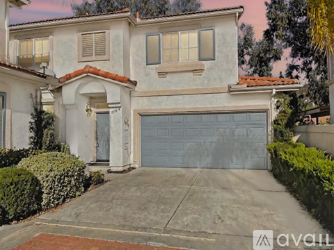 A two-story house with a garage door and a brick driveway.