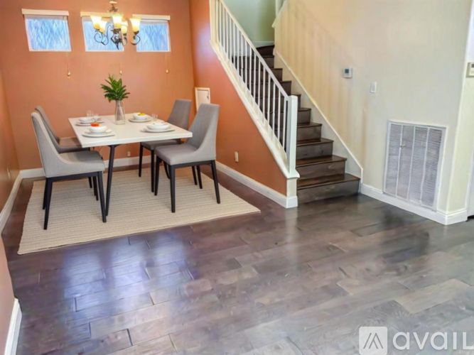 A dining room with a table set for two and a staircase.