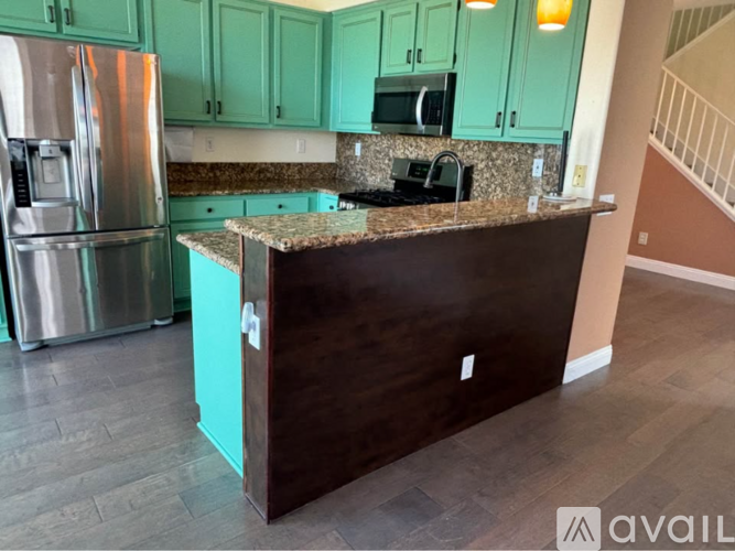 A kitchen with green cabinets and a stainless steel refrigerator.