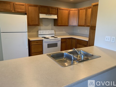 A kitchen with a white fridge, stove, and sink.