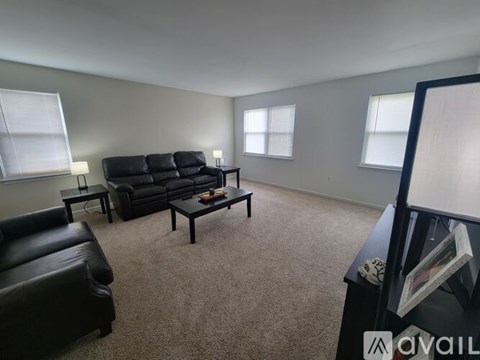 A living room with a black leather couch and a coffee table.