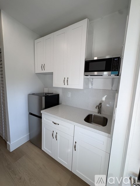 A kitchen with white cabinets and a black fridge.
