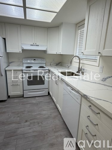 A kitchen with white cabinets and a white stove top oven.