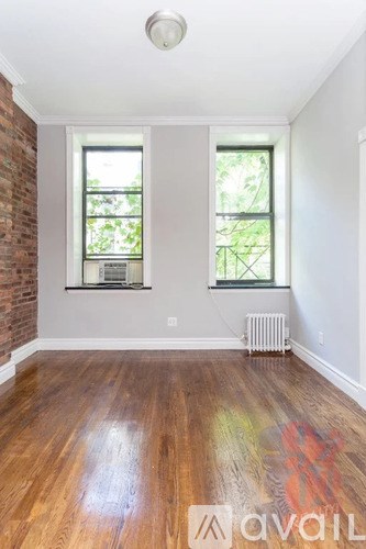 A room with wooden floors and two windows.