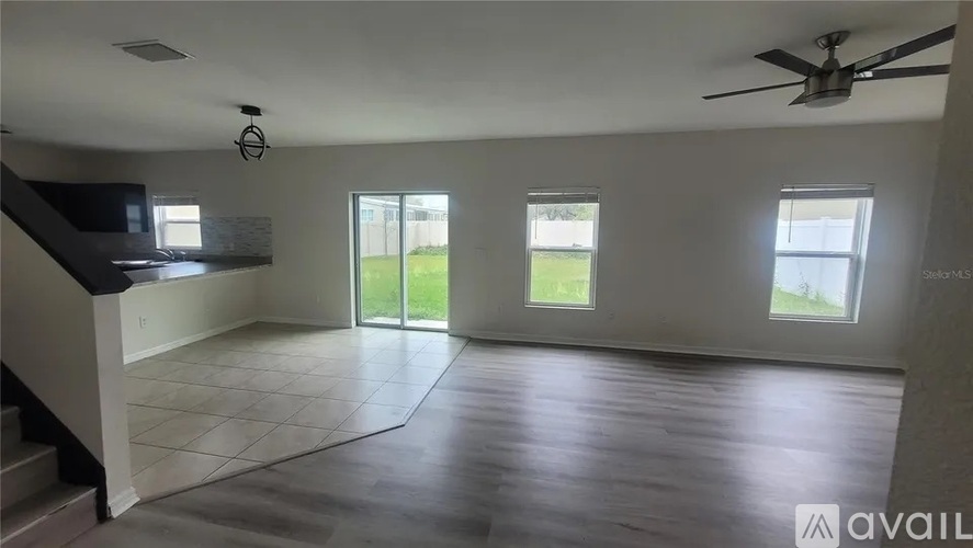 A spacious room with a staircase on the left and a ceiling fan on the right.