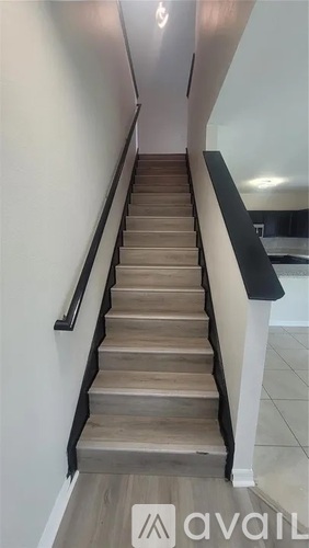 A staircase with wooden steps and a black handrail.