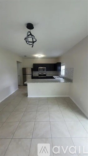 A kitchen area with a white counter and a hanging light fixture.
