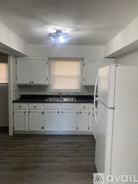 A kitchen with white cabinets and a white refrigerator.