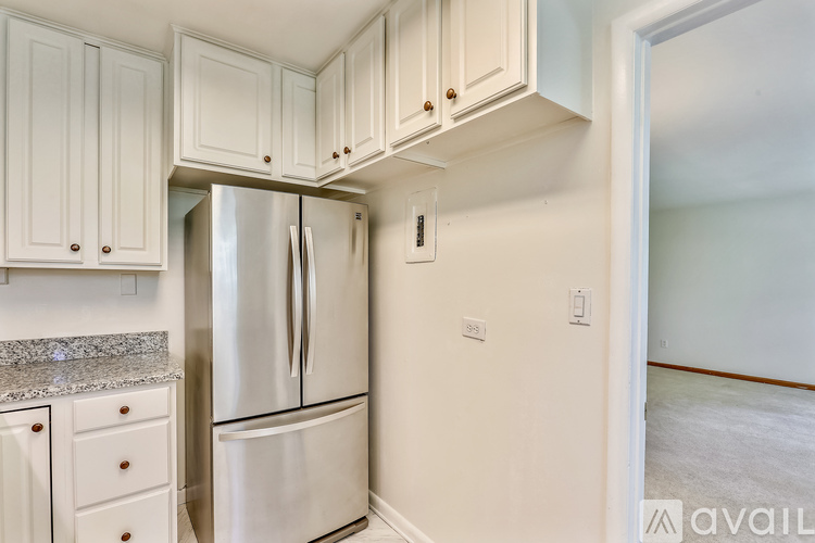 A kitchen with white cabinets and a stainless steel refrigerator.