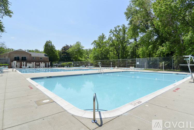 A large outdoor swimming pool surrounded by a fence and trees.