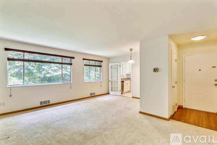 A spacious room with a large window and a door leading to another room.