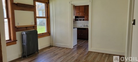 A room with a radiator and a window leading to a kitchen.