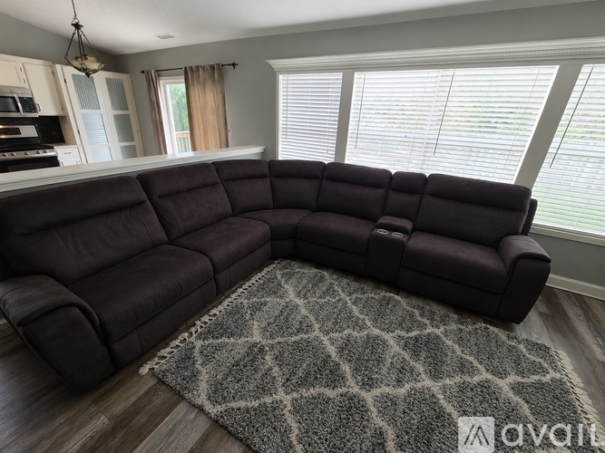 A grey sofa in a living room with a rug on the floor.