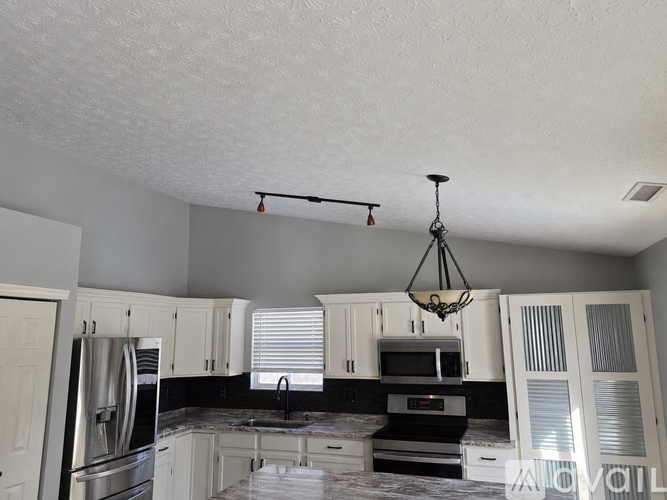 A kitchen with white cabinets and a black countertop.
