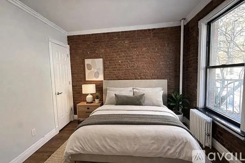 A bedroom with a large bed and a brick wall.