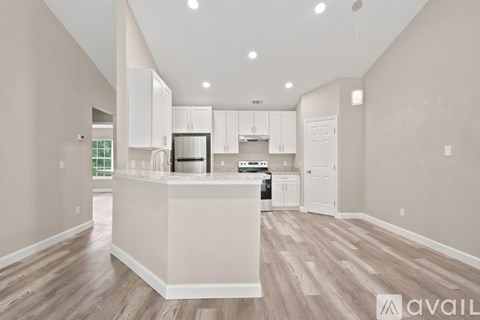 A kitchen with white cabinets and a wooden floor.