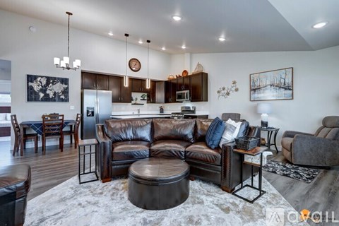 A modern living room with a brown leather couch and a grey rug.