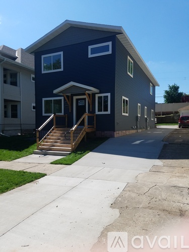 A blue house with a porch and a car parked in front.