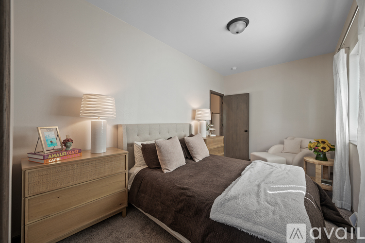 A well-lit bedroom with a large bed and a wooden dresser.