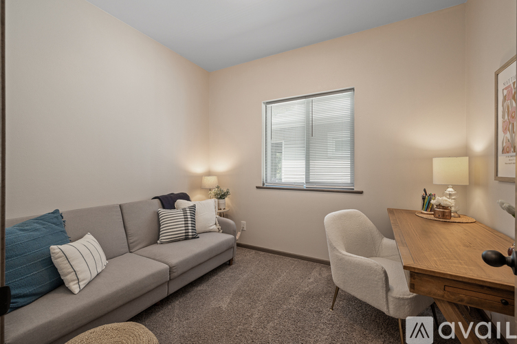A living room with a grey couch, a white chair, and a wooden table.