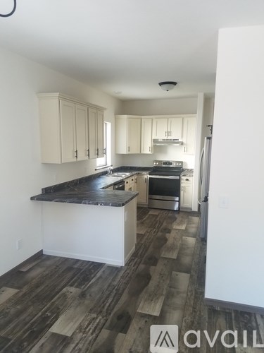 A kitchen with white cabinets and a black countertop.