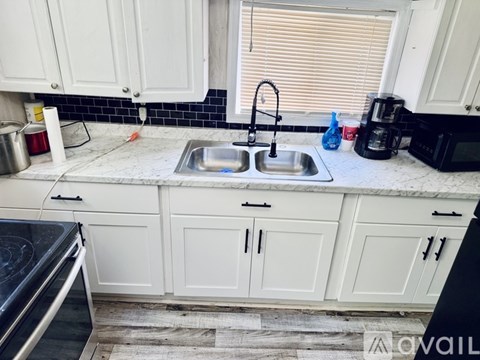 A kitchen with white cabinets and a marble countertop.