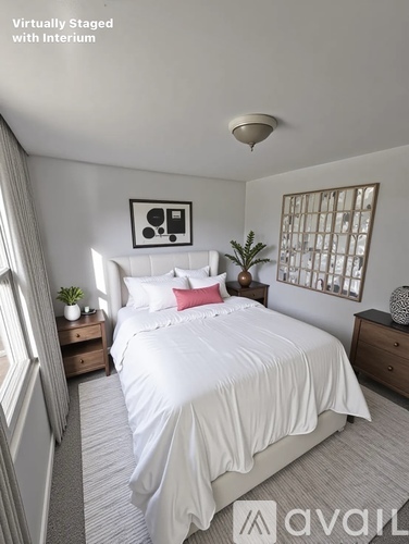 A bedroom with a white bed and a plant on the side table.
