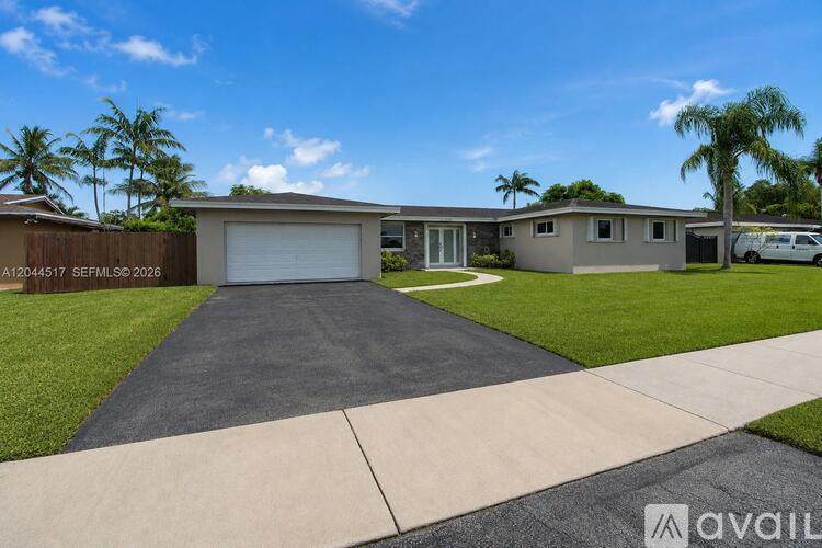A house with a driveway and palm trees in the background.