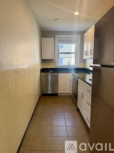 A kitchen with white cabinets and a tile floor.