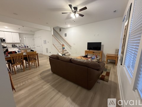 A living room with a brown couch and a television on a wooden stand.